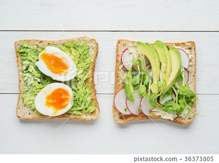 Two avocado toasts on white wooden background Two avocado toasts on white wooden background 36373805