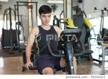 Attractive young man biking in the gym Attractive young man biking in the gym 36381821