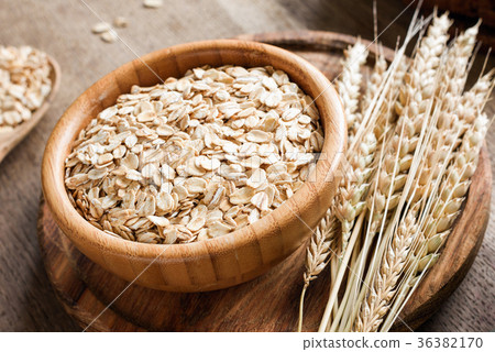 图库照片: rolled oats or oat flakes and golden wheat ears on