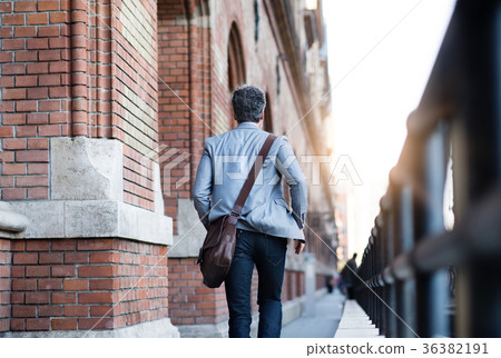 Mature businessman walking in a city. Mature businessman walking in a city. 36382191