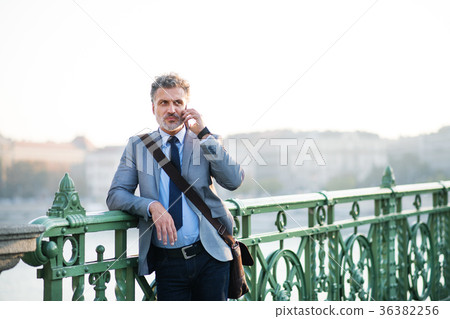 Mature businessman with a smartphone in a city. Mature businessman with a smartphone in a city. 36382256
