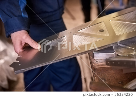 Hand holding metal part. 36384220