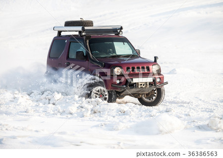 Red SUV riding on snow and snowflakes flying  36386563
