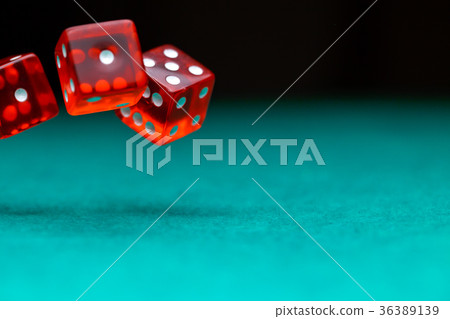 Picture of several red dice falling on green table 36389139