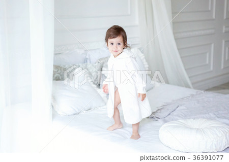 Cute little girl jumping on white bed Cute little girl jumping on white bed 36391077