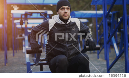 Muscular young man doing exercise in outdoor gym Muscular young man doing exercise in outdoor gym 36394216