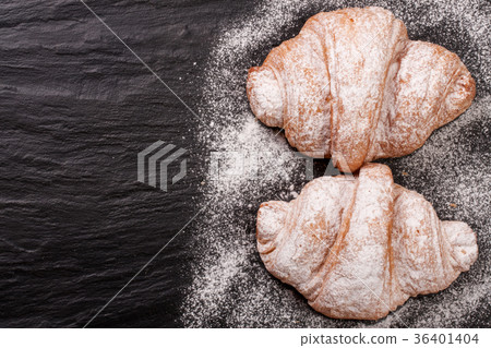 two croissant sprinkled with powdered sugar on two croissant sprinkled with powdered sugar on 36401404