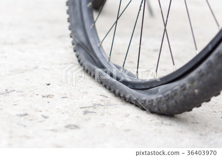 Bicycle wheel with flat tyre on the concrete road. 36403970