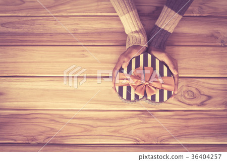 Hand holding heart gift box shape on wooden Hand holding heart gift box shape on wooden 36404257