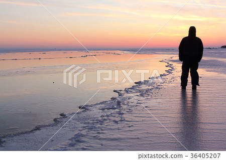 Man standing on the frozen river at sunset Man standing on the frozen river at sunset 36405207