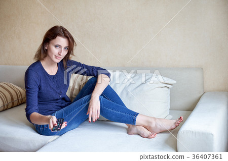woman relaxing in living room holding remote 36407361