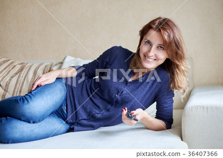 woman relaxing in living room holding remote woman relaxing in living room holding remote 36407366