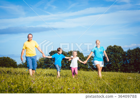 Family holding hands running over meadow Family holding hands running over meadow 36409788