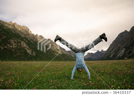 woman doing a handstand on mountain meadow woman doing a handstand on mountain meadow 36410337