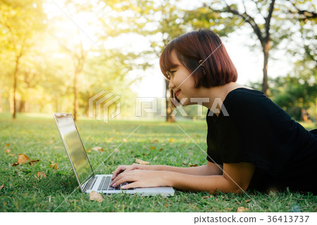 Young asian woman working on laptop in park. 36413737