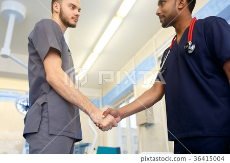 Two young Doctors shaking hands to each other Two young Doctors shaking hands to each other 36415004