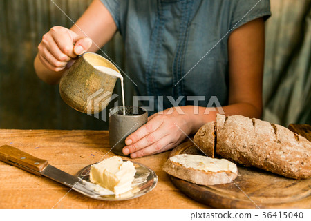Woman has breakfast adds milk to coffee 36415040