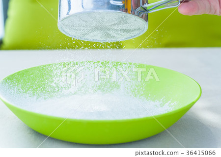 Sifting sugar powder in green bowl 36415066