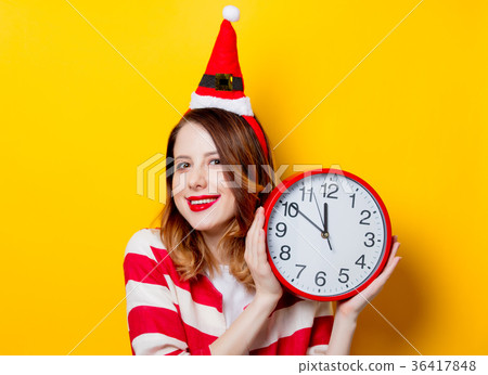 Smiling woman in Santa Claus hat with clock Smiling woman in Santa Claus hat with clock 36417848