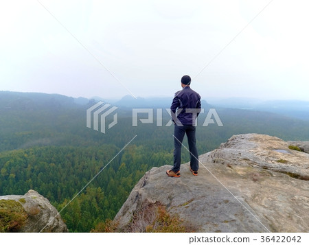 Nature hiker on sharp cliff roc watching over mist 36422042