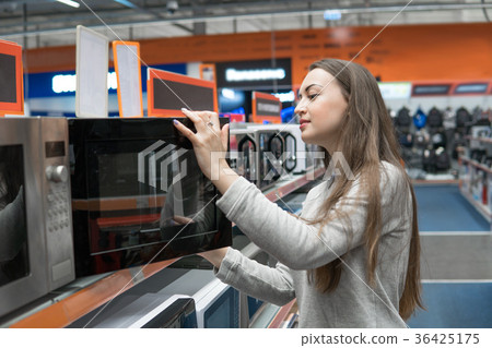 customer girl chooses a microwave oven in a home 36425175