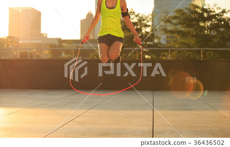 woman jumping rope at sunrise city building roof 36436502