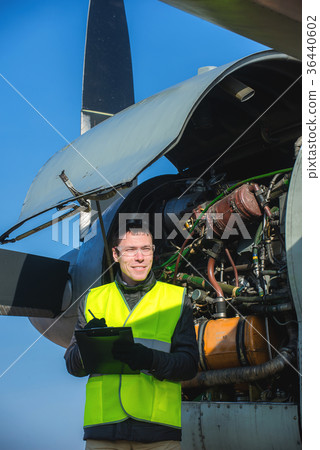 Mechanic checking airplane's engine 36440602