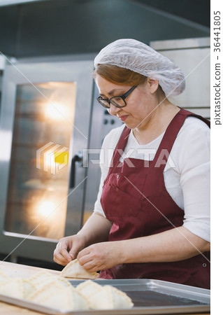 Adult woman in glasses and apron bakes cakes in Adult woman in glasses and apron bakes cakes in 36441805