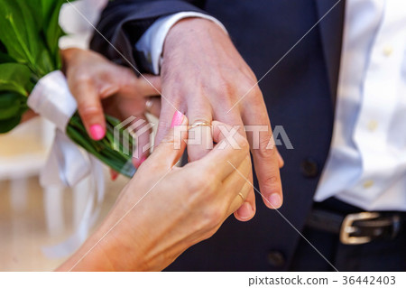 the bride wears a ring to the groom 36442403