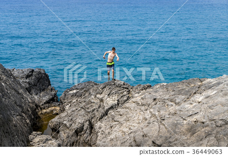 young man on a cliff getting out of balance 36449063
