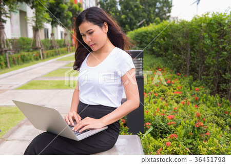 Young woman using computer laptop on garden bench 36451798