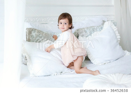 Cute little girl jumping on white bed Cute little girl jumping on white bed 36452638