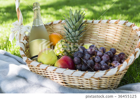 Wicker basket with fruits, champagne on grass 36455125