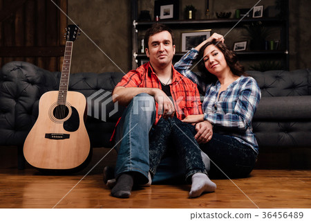 couple is sitting on the couch with a guitar. Long couple is sitting on the couch with a guitar. Long 36456489