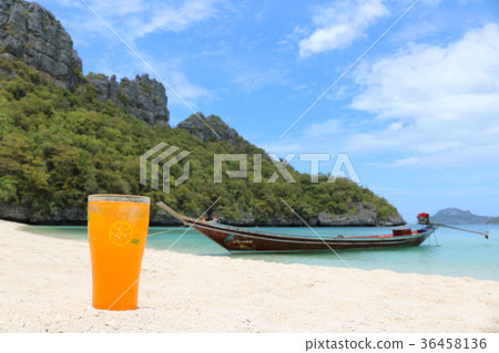 Glass of orange juice on the beach with ocean view 36458136