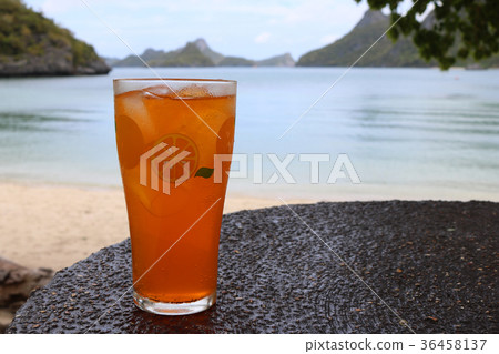 Glass of orange juice on the beach with ocean view Glass of orange juice on the beach with ocean view 36458137