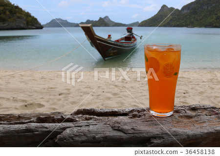 Glass of orange juice on the beach with ocean view Glass of orange juice on the beach with ocean view 36458138