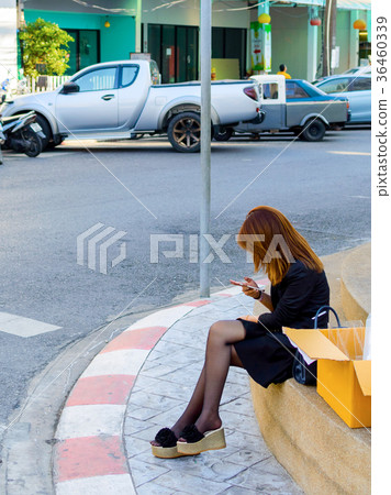 Woman using a smartphone sitting on a steps Woman using a smartphone sitting on a steps 36460339
