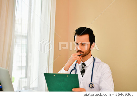 Smiling doctor posing in the office, he is wearing a stethoscope Smiling doctor posing in the office, he is wearing a stethoscope 36469363