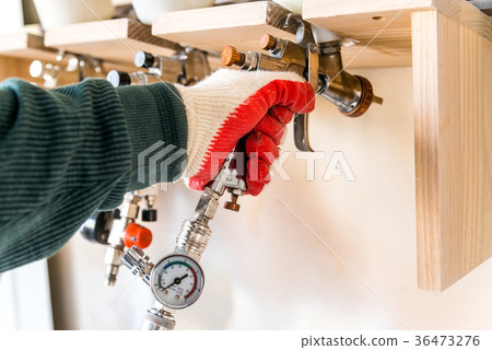 Hand takes spray gun in woodworking workshop Hand takes spray gun in woodworking workshop 36473276