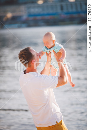 A young father holds one year of his son in arms 36476980
