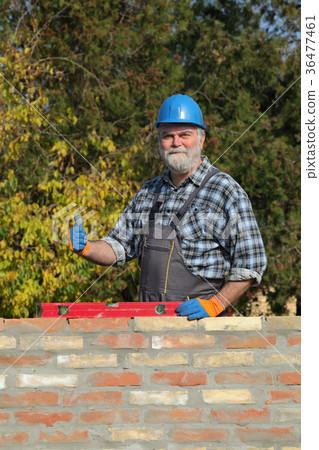 Worker examining brick wall 36477461
