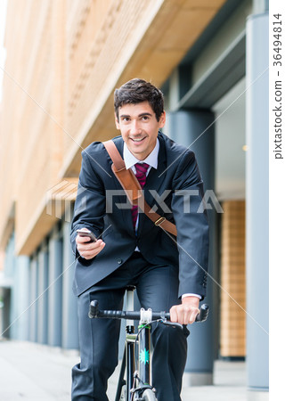 Multitasking young businessman riding a bicycle to Multitasking young businessman riding a bicycle to 36494814