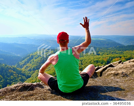 Slim body hiker in singlet and shorts sit on rock Slim body hiker in singlet and shorts sit on rock 36495036