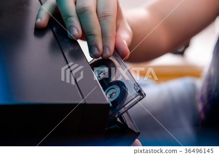 man put CD cassette into old cd audio player.  36496145