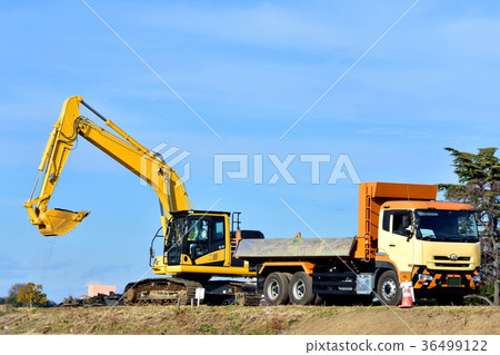 A hydraulic excavator loading asphalt rubble into a dump truck 36499122