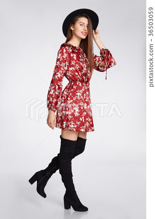 Attractive happy girl is possing and smilling in flower red dress and black hat on white Attractive happy girl is possing and smilling in flower red dress and black hat on white 36503059