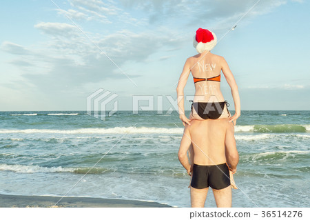 Girl in Santa hat sits on the shoulders of a guy Girl in Santa hat sits on the shoulders of a guy 36514276