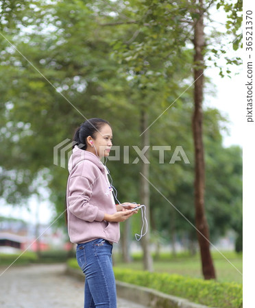 A woman listening to music on a smartphone 36521370