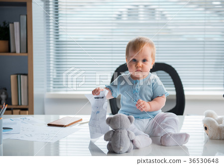 Serene kid sitting on table in room 36530648